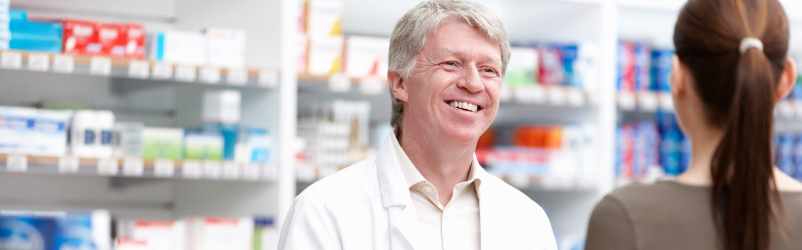 pharmacist behind counter smiling at patient