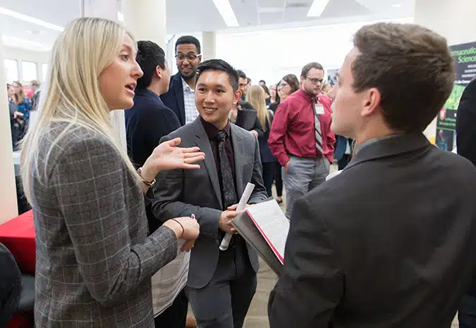 An employer answers questions for two pharmacy students at the career fair