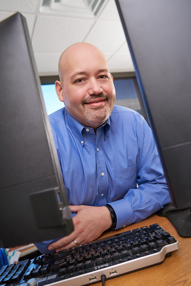 James Hoffman looks to the camera between two computer monitors