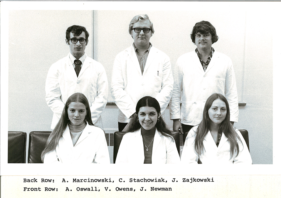 A black-and-white group photo of pharmacy students in white coats.