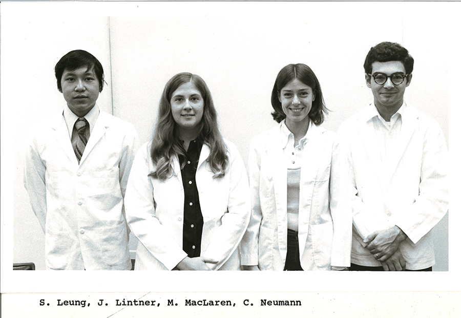 A black-and-white group photo of pharmacy students in white coats.