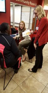 Third year pharmacy students Lauren Caruso (seated) and Alissa Hofer consult with an attendee at the AAHN event.