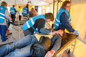 Mary Hayney (leaning over bed) assists a patient actor in triage during the drill.