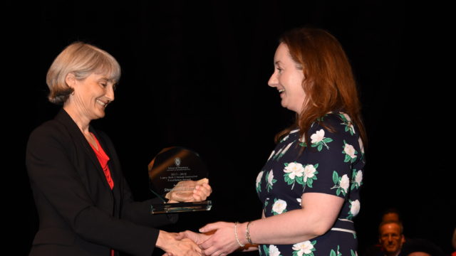 Mara Kieser handing Stephanie Root an award onstage
