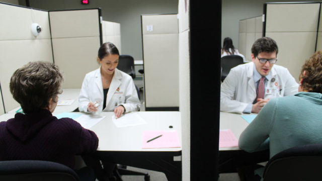 communications lab with students wearing white coats speaking to patients