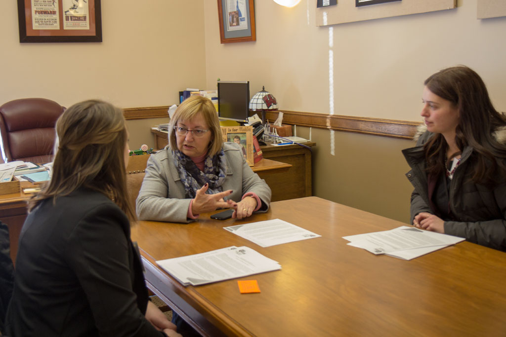 Pharmacy students speaking with a legislator at a table