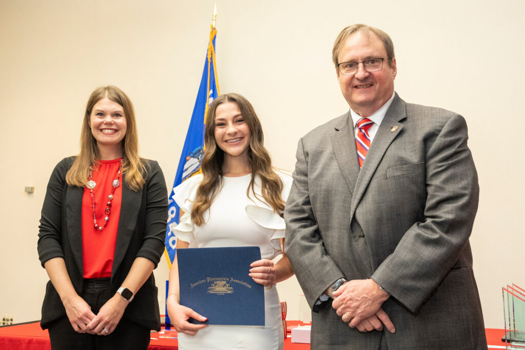 An award winner poses with Dean Steve Swanson and Andrea Porter.