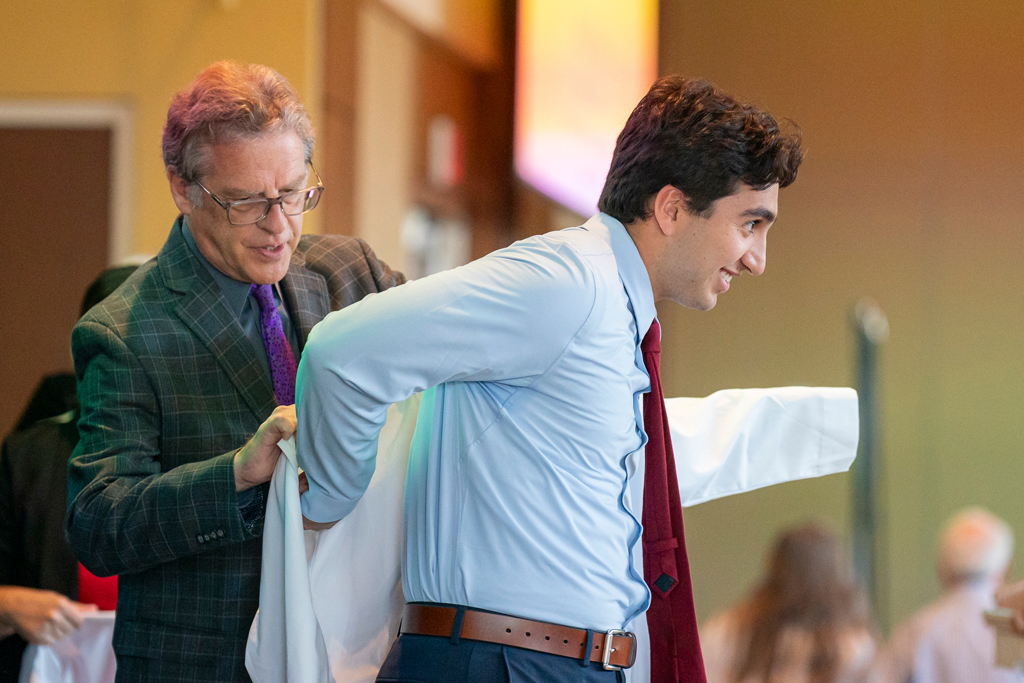 Staff helping student into white coat