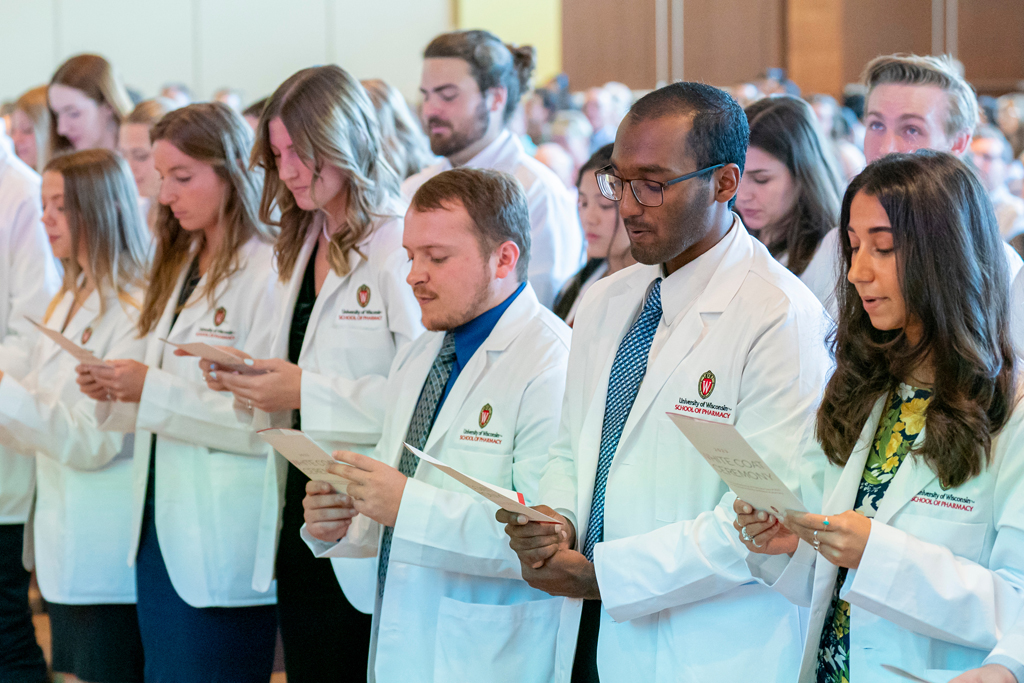 Students in white coats reading their flyers