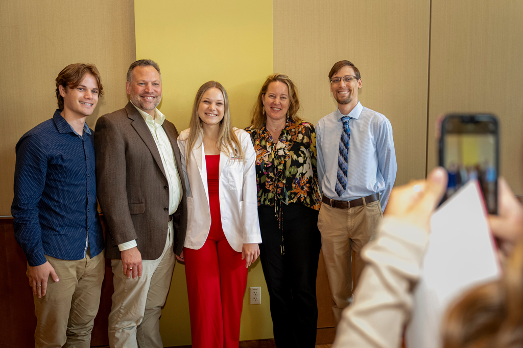 Student in white coat posing with family