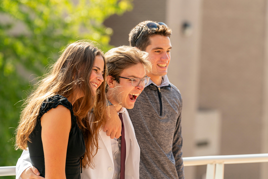 Student in white coat making silly face during group photo