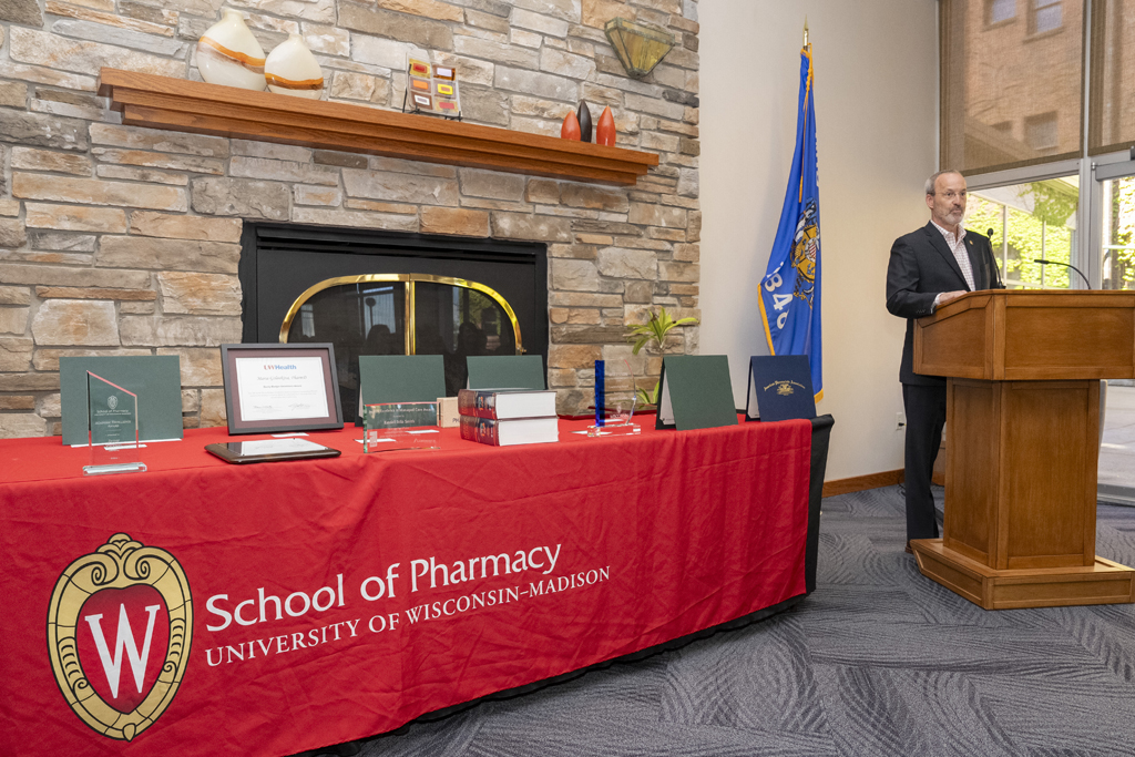 Dave Mott speaks at the podium next to a table full of awards