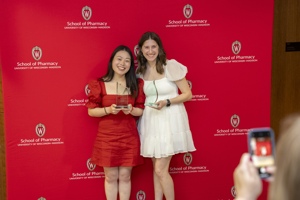 Two graduates pose with awards