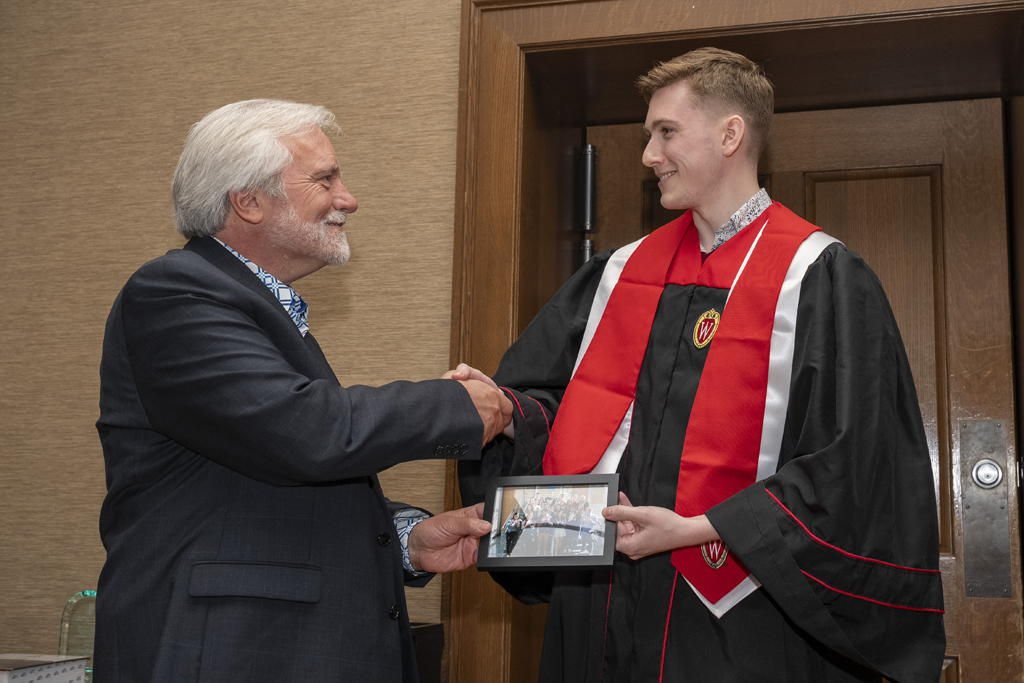 A student accepts a class photo from Jeff Johnson