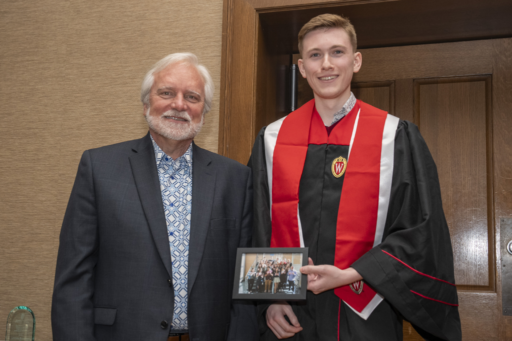 A student accepts a class photo from Jeff Johnson