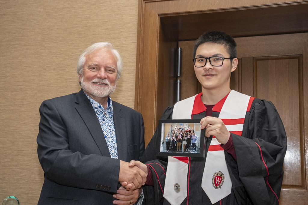 Ethan Cui accepts a class photo from Jeff Johnson