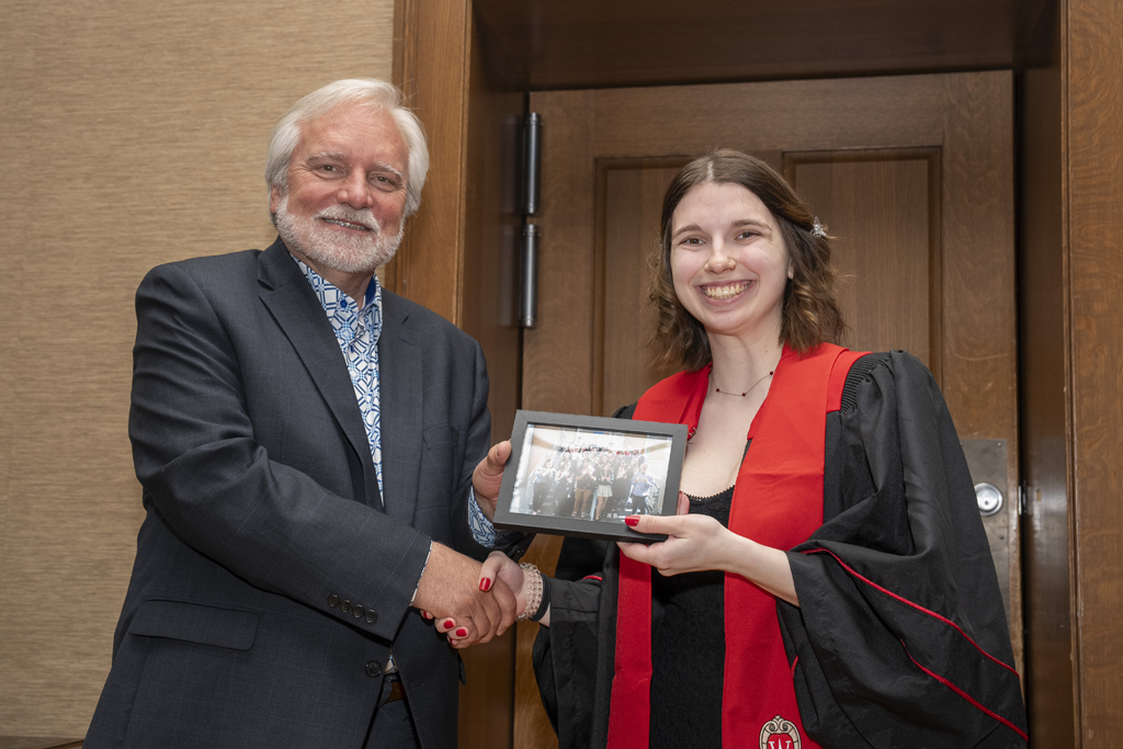A student accepts a class photo from Jeff Johnson