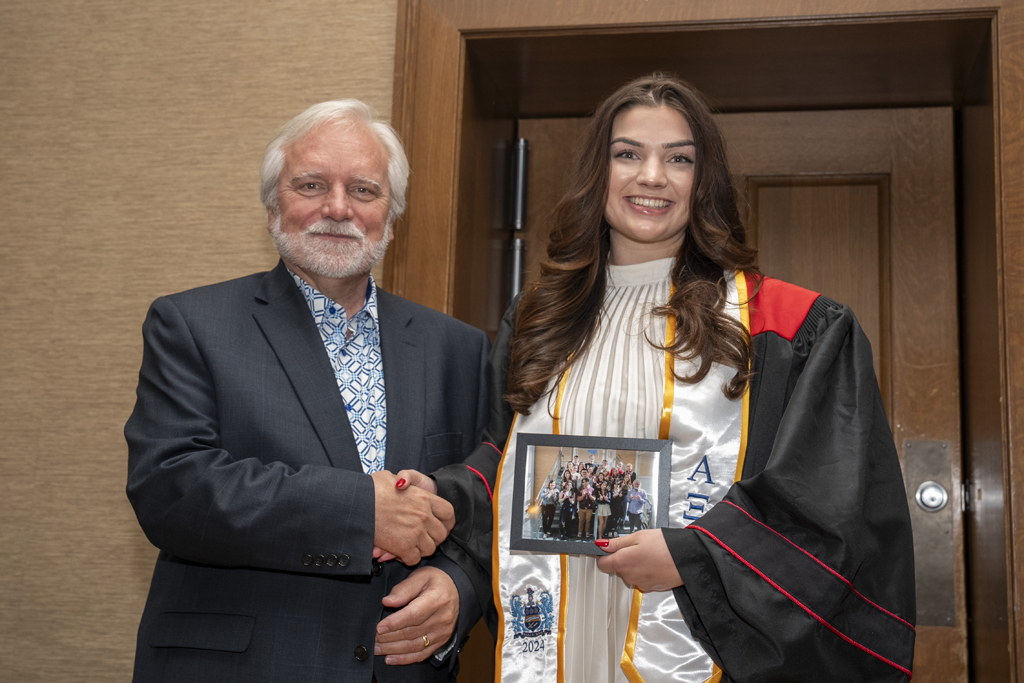 A student accepts a class photo from Jeff Johnson