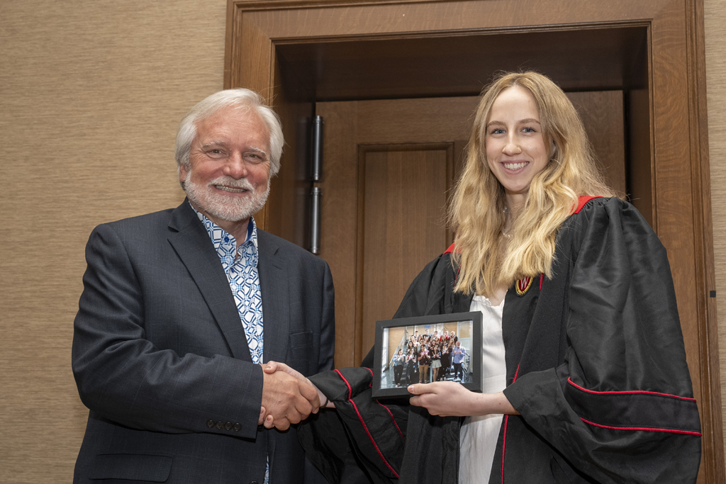 A student accepts a class photo from Jeff Johnson