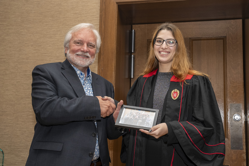 A student accepts a class photo from Jeff Johnson