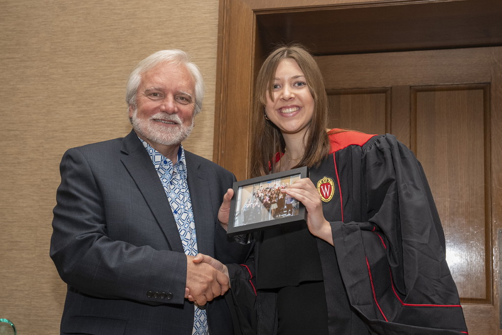 A student accepts a class photo from Jeff Johnson