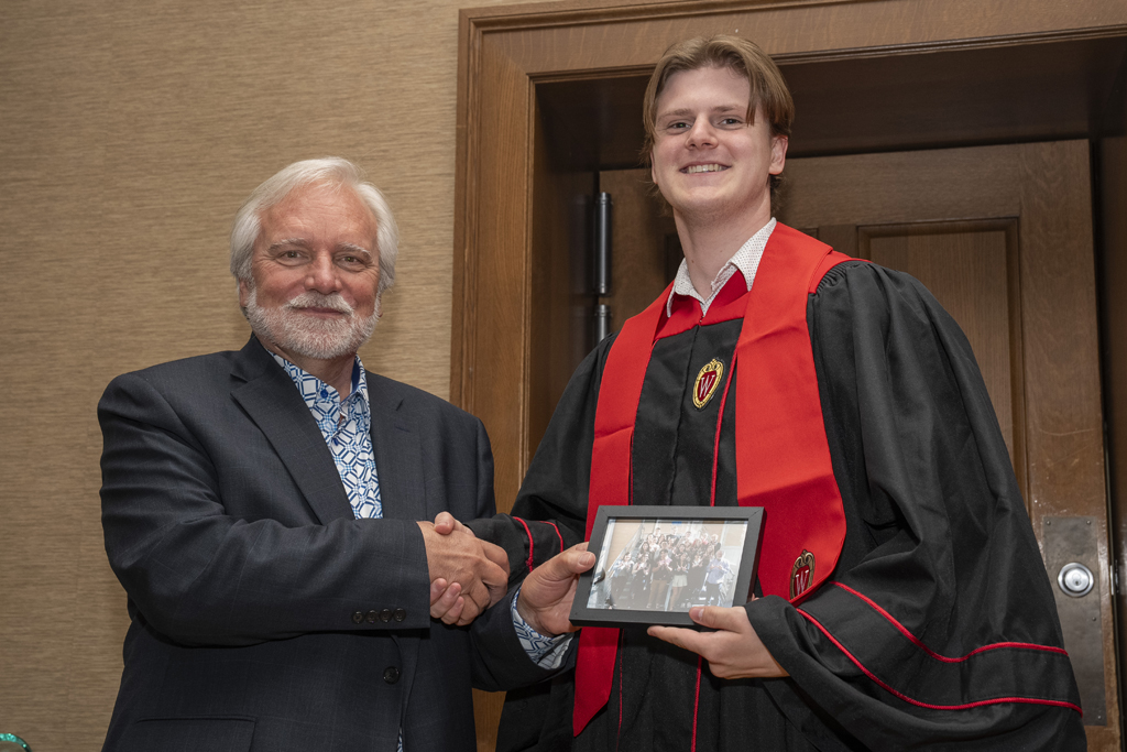 A student accepts a class photo from Jeff Johnson