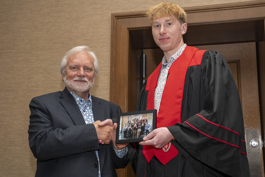 A student accepts a class photo from Jeff Johnson