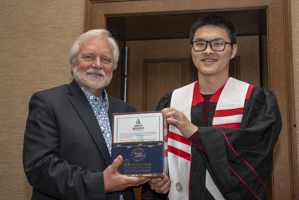 A student receives a Merck Award from Jeff Johnson