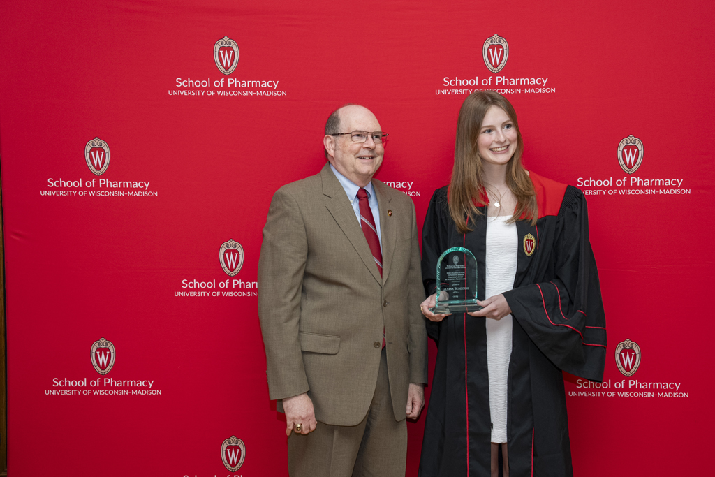 Ed Elder and a graduate pose with an award from the Zeeh Station