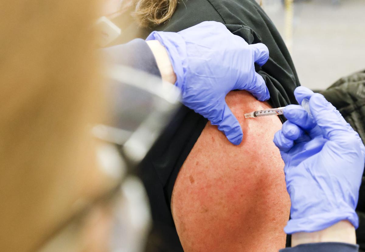 gloved hand administering covid vaccine to a patient