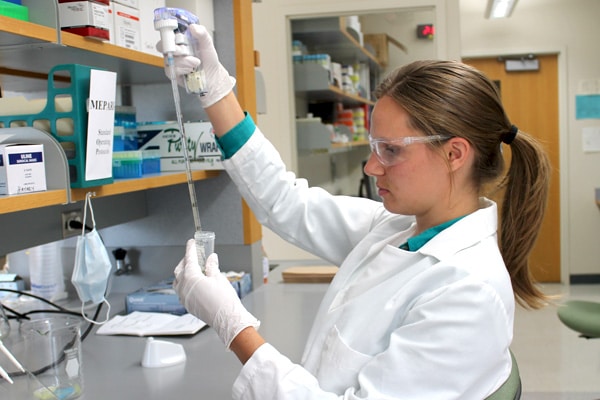 A lab employee pipettes liquid into a test tube