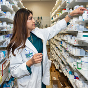 A pharmacist hunts for a prescription medication on the shelf