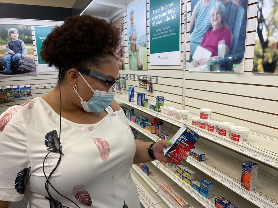 A woman wearing the eye-tracking glasses and looking at a pain and fever medication.