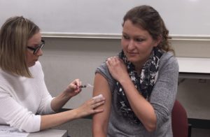 Niki Krancevich delivering a flu shot to Kellyn Engstrom