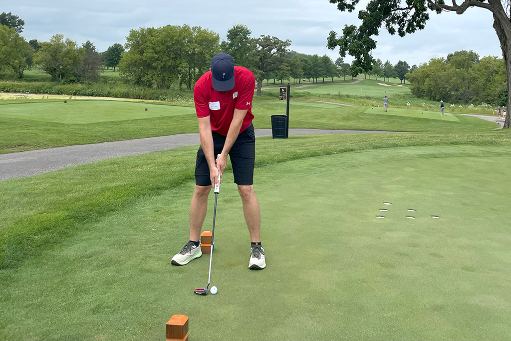 A male alum tees off