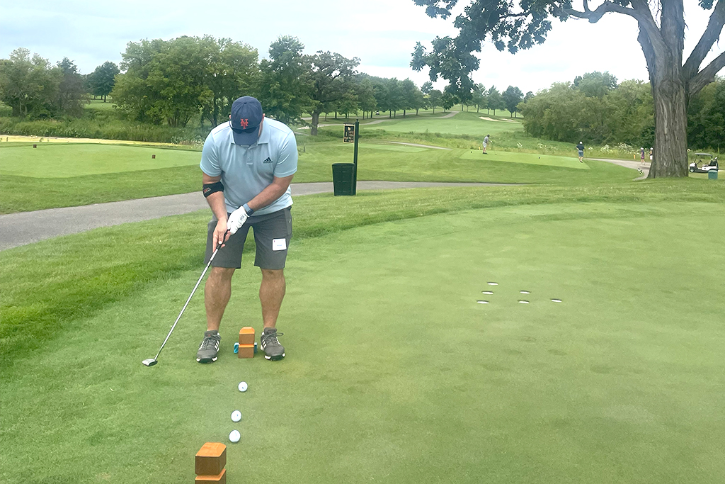 A male alum tees off