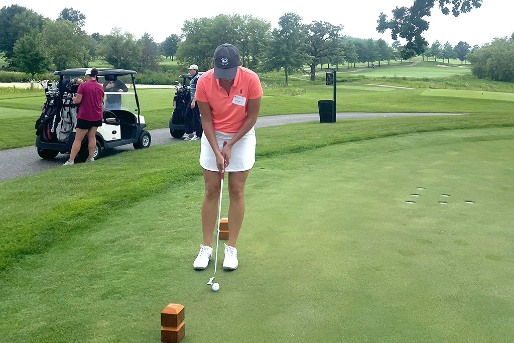 A female alum tees off
