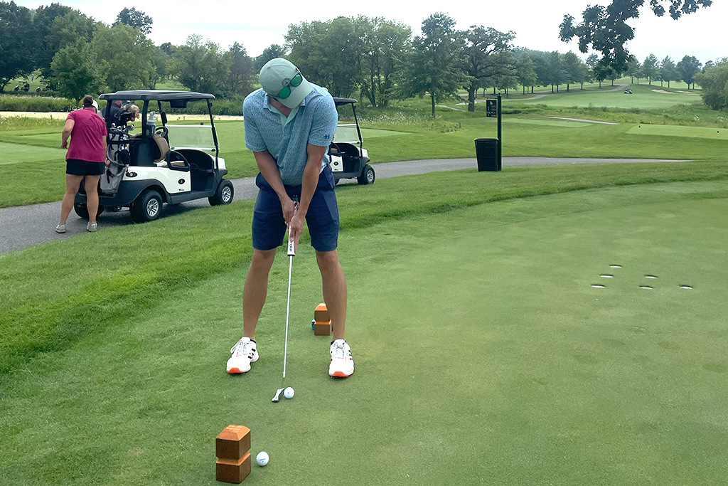A male alum tees off