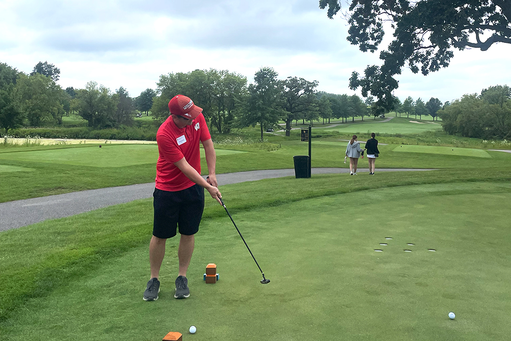 A male alum tees off