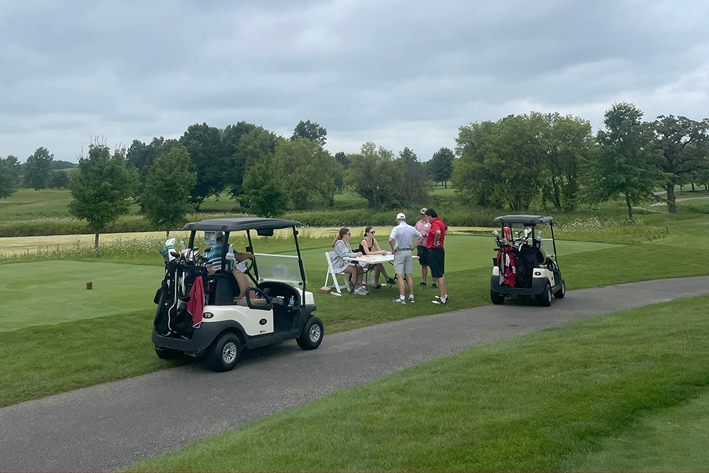 Alums at a check-in table near a golf cart
