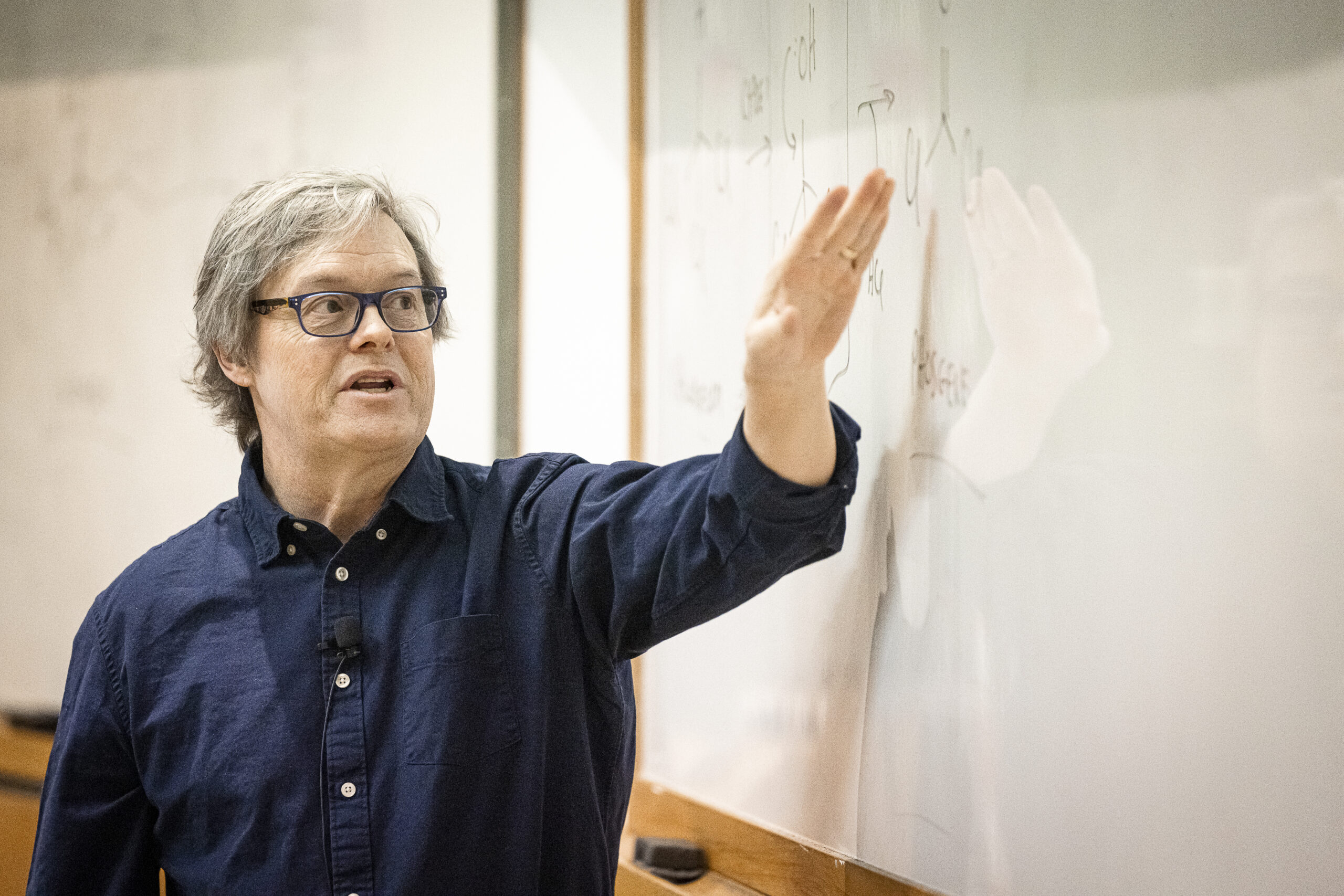 Charles Lauhon stands in front of a white board teaching a course