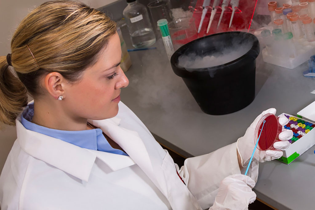 Laurel Legenza working with a substance in a petri dish and a bucket filled with smoke on the counter next to her