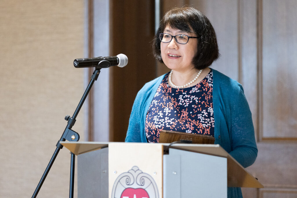 Jun Dai speaks at the podium.