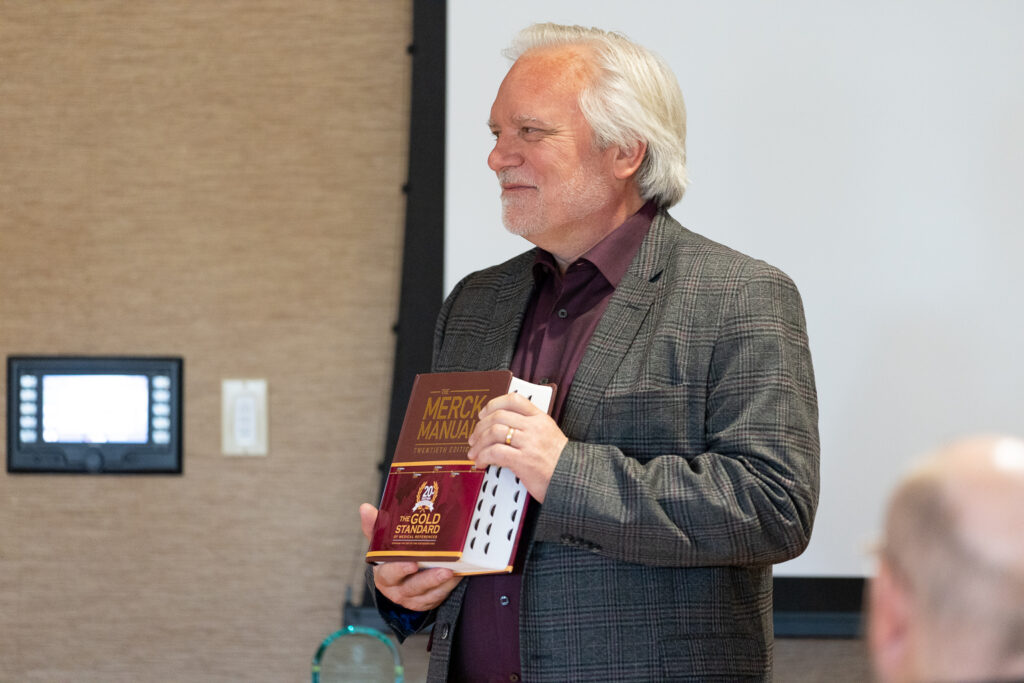 Jeff Johnson smiling with a Merck Manual.