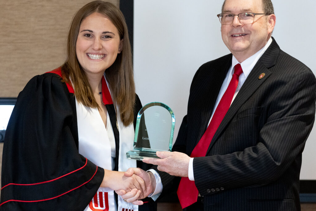 A PharmTox graduate and Ed Elder pose with an award.