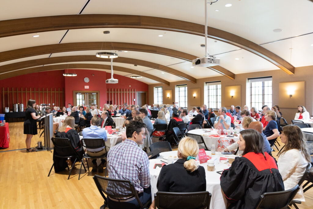 PharmTox graduates and their families seated at tables.
