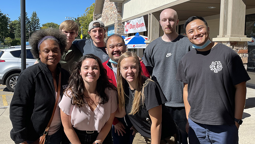 A smiling group of students with Professor Eva Vivian outside.