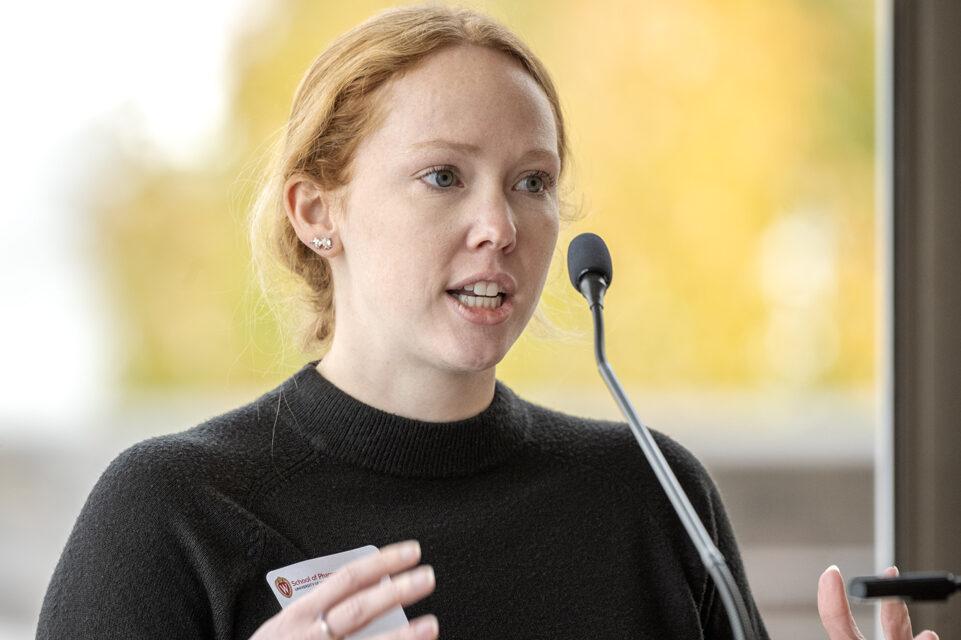 Heather Spatchek gesturing with hands and speaking into microphone at podium