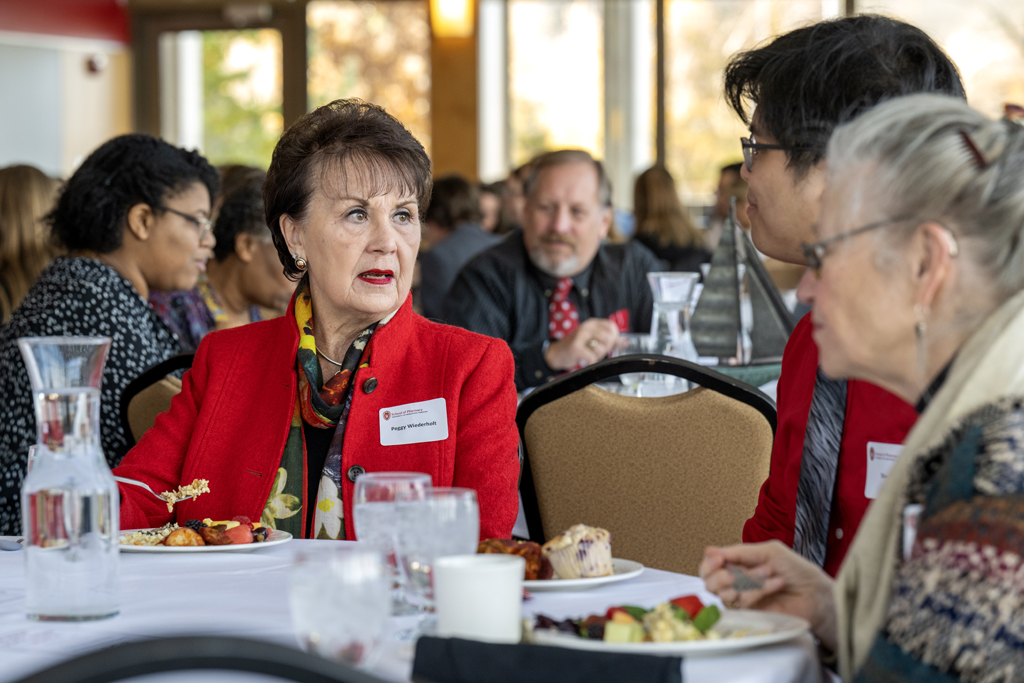 Peggy Wiederholt speaking to Steven Do and Betty Chewning while they're eating around table