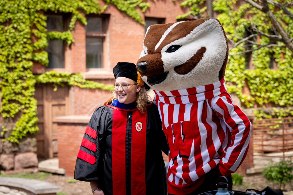 A graduate poses with Bucky Badger